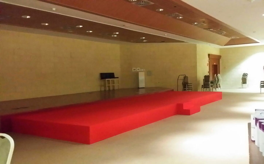 Escenario para presentación con moqueta roja y escalera acceso